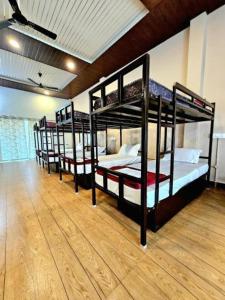 three bunk beds in a room with a wooden floor at LEO DREAM HAMPi in New Hampi