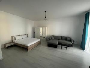 a white bedroom with a bed and a couch at VISAJ Metropolitan - authorized by the Ministry of Tourism in Giroc