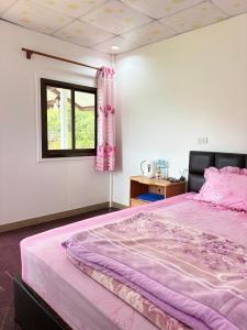a bedroom with a pink bed and a window at บ้านพักสมพงศ์ภูทับเบิก in Ban Maeo Thap Boek