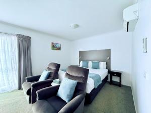 a hotel room with a bed and two chairs at BKs Premier Motel Hamilton in Hamilton