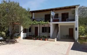 a large white house with stairs and a tree at Apartmani Sekana in Starigrad