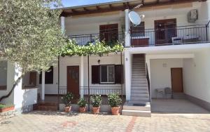 a white house with a staircase and potted plants at Apartmani Sekana in Starigrad