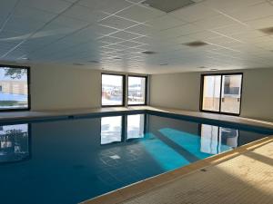 a swimming pool with blue water in a room with windows at Le cocon du télésiège - Piscine chauffée - Métabief in Métabief +7 photos