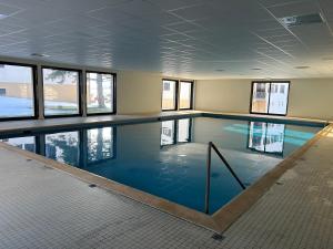 a large swimming pool with blue water in a building at Le cocon du télésiège - Piscine chauffée - Métabief in Métabief