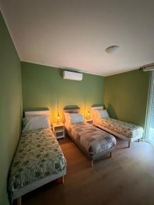two beds in a room with green walls at 88 Destination in Treviglio