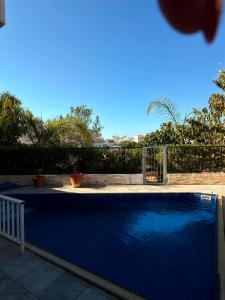 a blue swimming pool with a fence and trees at Seana Hidden Gem in Kapparis in Paralimni