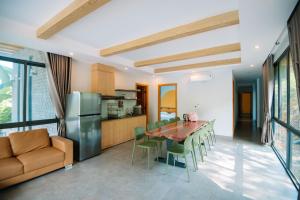 a kitchen and dining room with a table and a refrigerator at Daisy Queen Village Ba Vì in Yên Cư