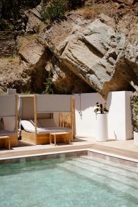 a pool with a bed and chairs next to a rock at Casamore in Meria