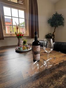 a bottle of wine sitting on a wooden table with a glass at Vakantiewoning Uutbloazen in Lievelde
