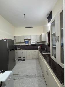 a kitchen with white cabinets and a black refrigerator at Stay at Renovated Home at DBRA-61 Don Bosco Cross Road Vaduthala Ernakulam in Cochin