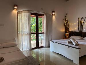 a bedroom with two beds and a large window at Papaya Hikkaduwa in Hikkaduwa