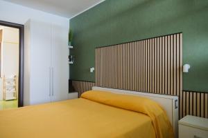 a bedroom with a yellow bed with a green wall at Villa Serra d'Elci in Ascea