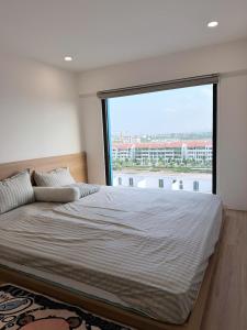 a bedroom with a large bed with a large window at Ong Vàng in Quang Ãm