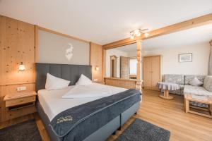 a bedroom with a bed and a couch and a chair at Hotel Schönegg in Seefeld in Tirol