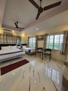 a bedroom with two beds and chairs and windows at Hotel Shreesh Mayapur in mayapur