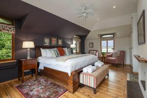 a bedroom with a large bed and a chair at Glen Eden Lodge in Lidgetton +109 photos