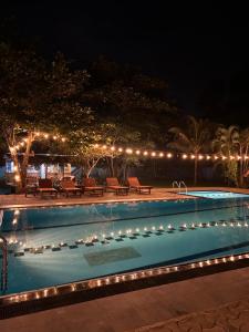 a swimming pool lit up at night with lights at Papaya Hikkaduwa in Hikkaduwa