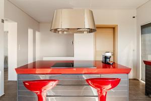 a kitchen with red counters and red stools at White Sand Loutraki Villa - Sea View in Loutraki