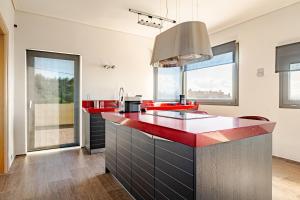 a kitchen with red and black counters and windows at White Sand Loutraki Villa - Sea View in Loutraki