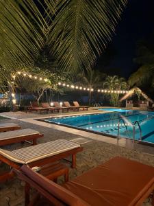 a swimming pool at night with benches around it at Papaya Hikkaduwa in Hikkaduwa +17 photos