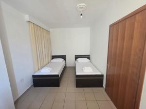 two beds in a small room with a door at Comfort Saranda Apartment in Sarandë
