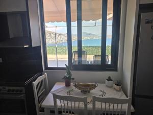 a table and chairs in a kitchen with a window at Comfort Saranda Apartment in Sarandë