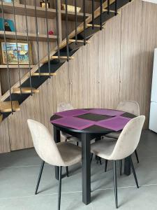 a purple table and chairs in a room with stairs at Charmant petit maison in Pontorson