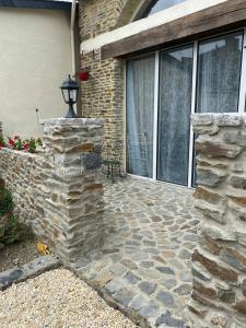 a patio with a stone wall next to a house at Charmant petit maison in Pontorson