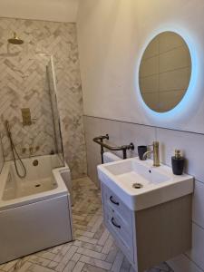 a bathroom with a sink and a tub and a mirror at Grange House Budget Rooms in Leeds +30 photos