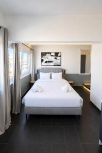 a large white bed in a room with windows at The Athenian Pearl in Athens