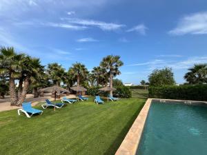 a pool with chairs and umbrellas on a lawn at Masia Botargo. 9 hab, 8 baños, piscina, porche in L'Aldea