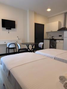two beds in a room with a table and a kitchen at Mzeonas Apartment in Kobuleti