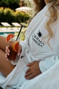 a woman is holding a drink with an orange slice at THERMA NUMERA Mineral SPA & Longevity in Burgas