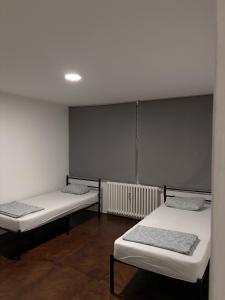 two beds in a room with white walls and wooden floors at Apartman City 2 With 2 Bedrooms and Free Parking in Negotin
