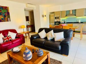 a living room with a black leather couch and a table at Santa Maria Ilha do Sal T2 Apartament with pool A&L em Vila Verde in Prainha