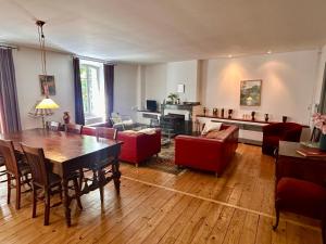 a living room with a table and red chairs at Notre-Dame d'Escouloubre Sources d'eaux chaudes privées et sauna in Escouloubre