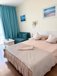 a bedroom with a large bed and a blue chair at Adela Sunset View by Blaxy Resort in Olimp