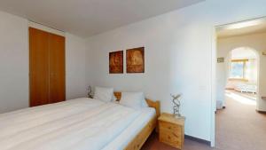 a white bedroom with a large bed and a window at Residenz Alpina im Kurhaus in Lenzerheide