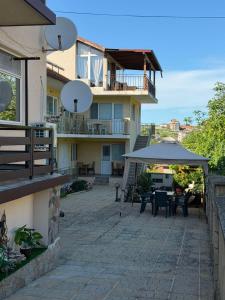 a building with a patio with tables and an umbrella at Eleonor Guest House in Byala