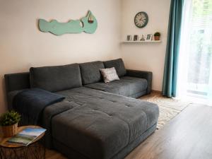 a gray couch in a living room with a clock at FoBala Apartman in Balatonföldvár +32 photos