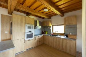 a large kitchen with wooden cabinets and white appliances at Chata Michala in Dolný Kubín +6 photos