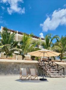 two chairs and an umbrella on a beach at Tangawizi Lodge Zanzibar - Adults Only in Jambiani