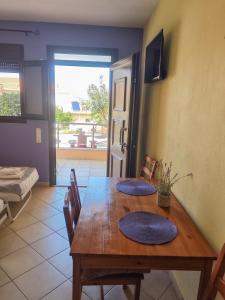 a dining room with a wooden table with blue mats on it at Lavender Apartments in Skala Potamias