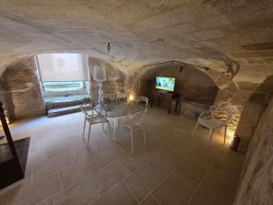 a dining room with a table and a tv in a cave at Dimora Pietra E Luce By Cala Salento in Vignacastrisi