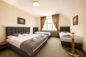 a bedroom with two beds and a table in it at Hotel Bergwirt Schönbrunn in Vienna