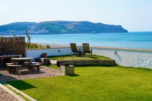 two chairs and a picnic table on the beach at Superb Cintra Beachside Apartments in Llandudno