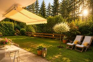 a backyard with two chairs and an umbrella at Ferienwohnung Wilder Kaiser & Kitzbüheler Alpen Garten & Terrasse SkiWelt & Hohe Salve ITD099 in Itter