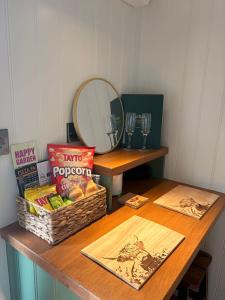a table with a basket of snacks and a mirror at Everwood Escape- The Willow Hut With Private Hot Tub in Dungiven +11 photos