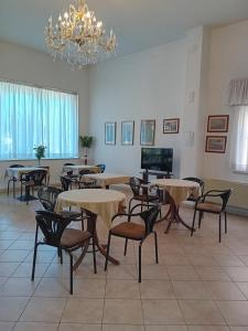 ein Zimmer mit Tischen und Stühlen und einem Kronleuchter in der Unterkunft Hotel Cucciolo in Donoratico