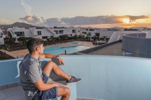 a man sitting on the ledge of a roof at Ático de Lujo con Jacuzzi Privado en Azotea Vistas in La Oliva